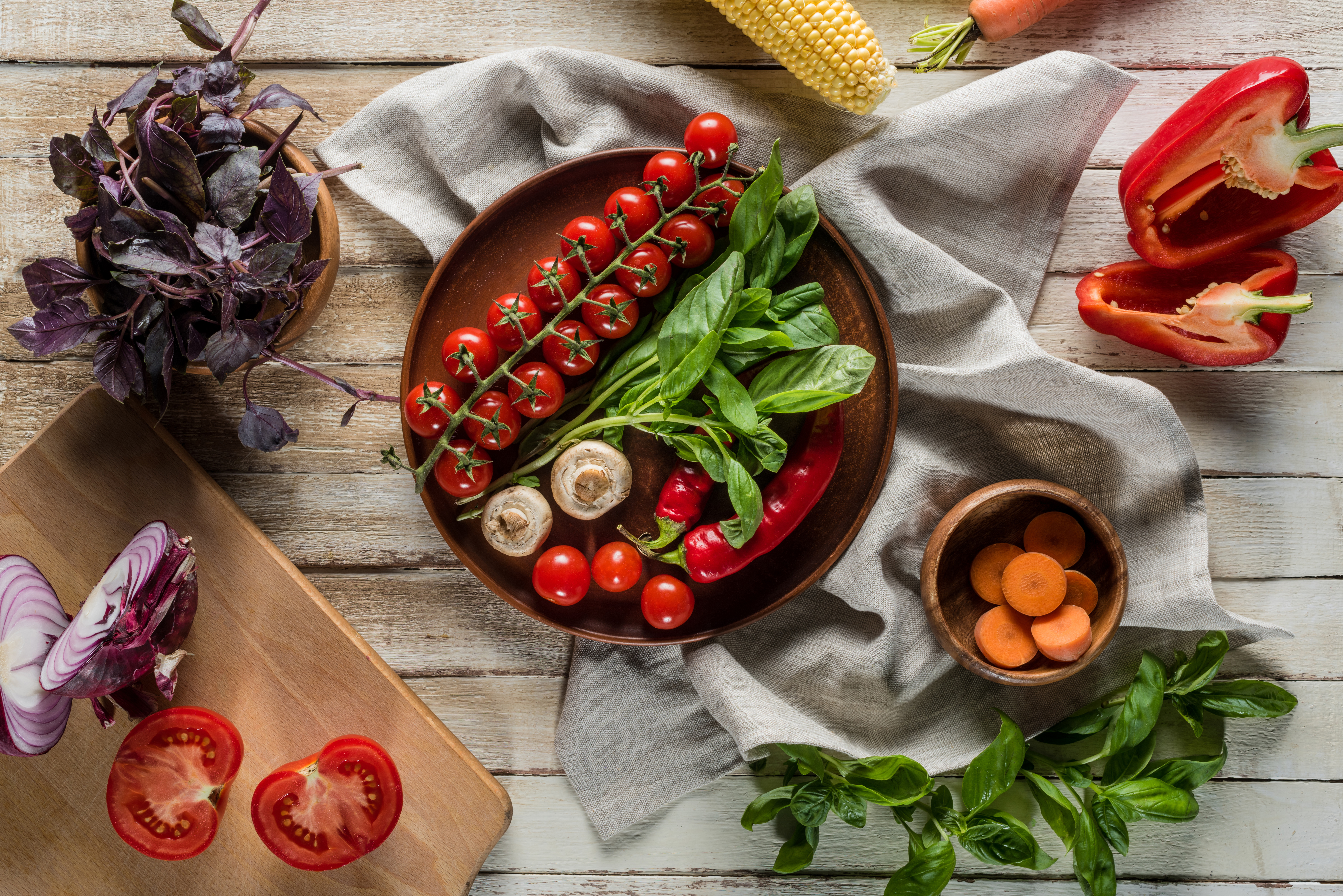 top view of organic fresh vegetables with napkin on wooden tabletop